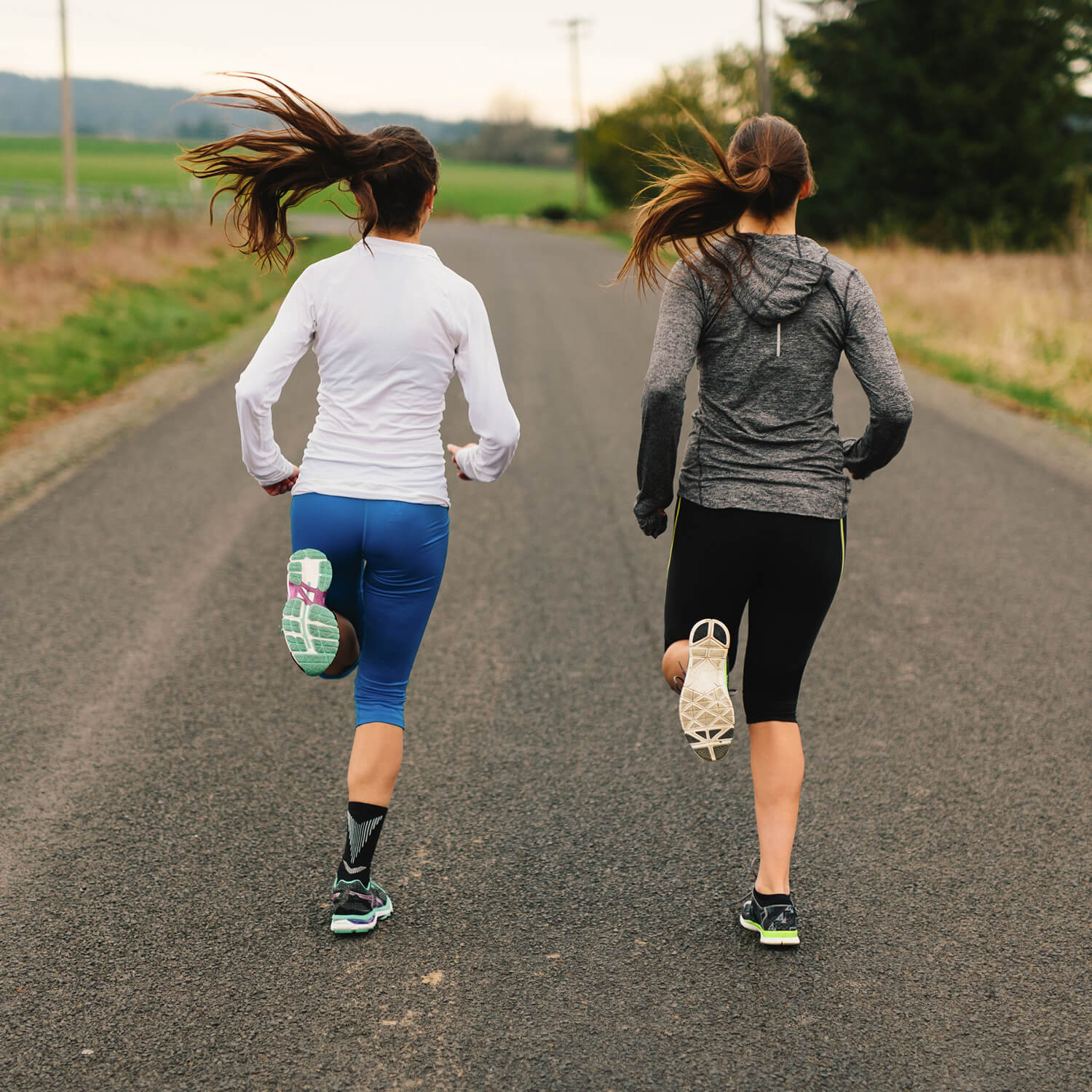 2 women running together down a road. 